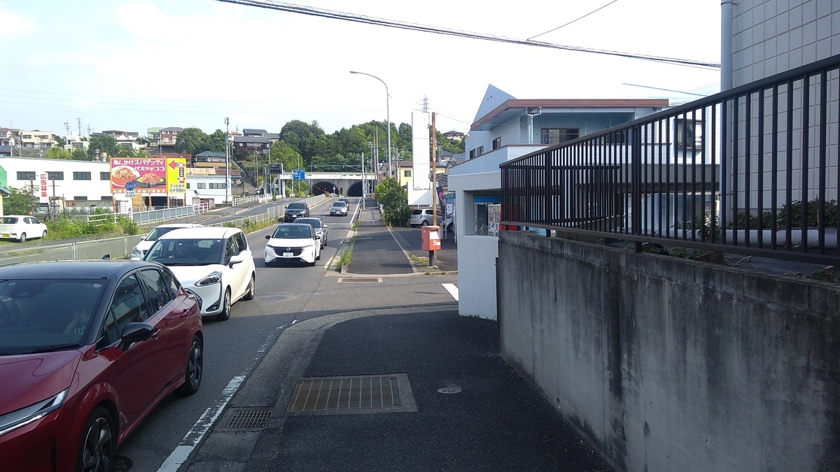 A view down a road ending in a twin tunnel under a hill in the distance.