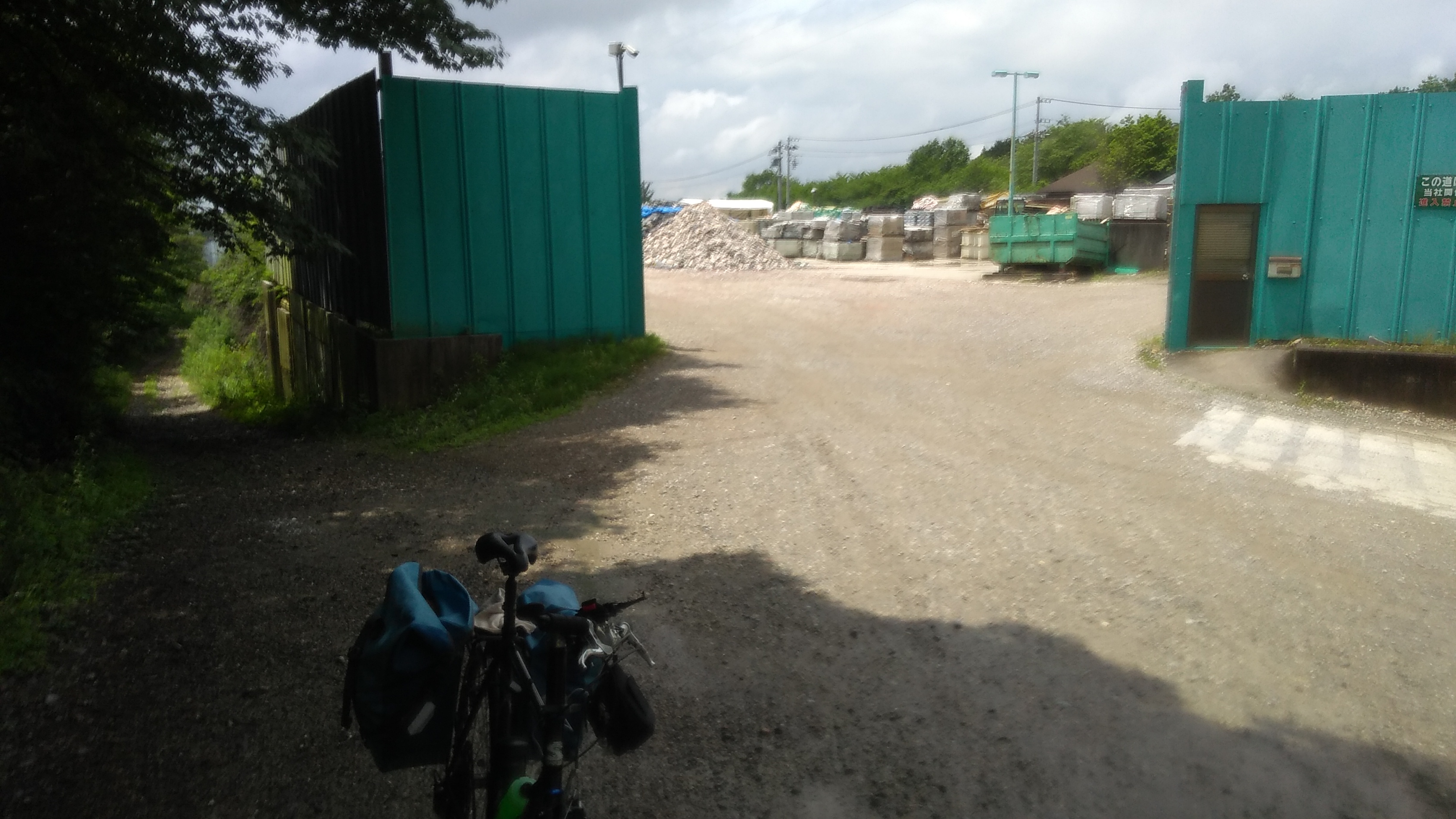 The entrance to a gravel works, flanked by 3 meter tall steel panels that enclose the site.