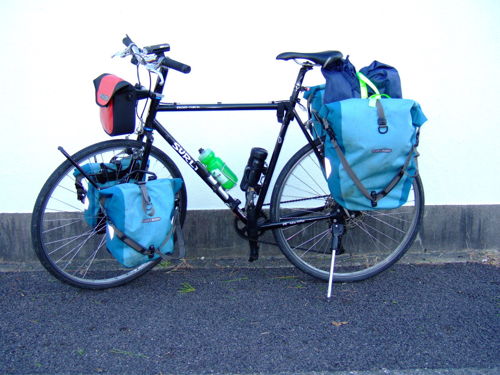 A black gravel bike by Surly loaded with denim-blue front and rear panniers.