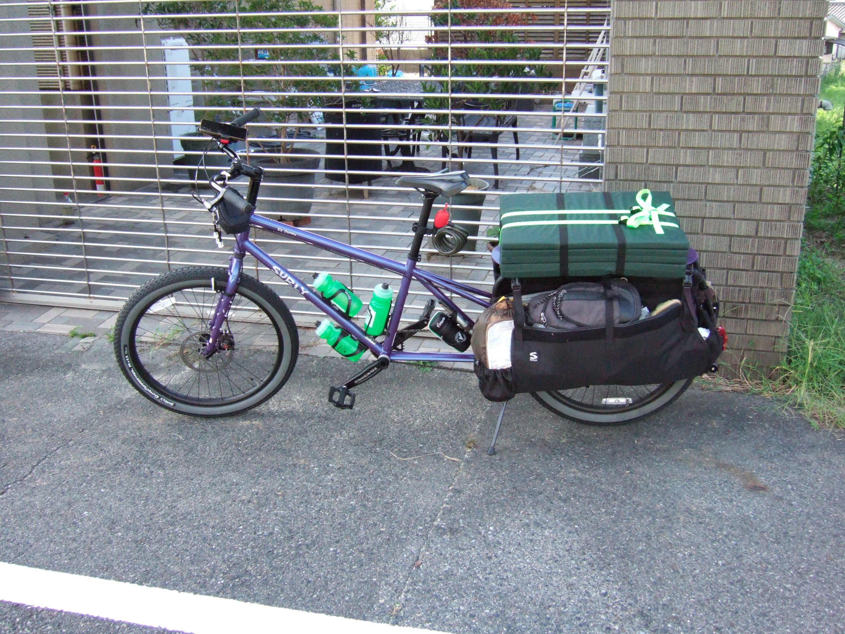 A cargo bike with a long frame, loaded with camping gear.