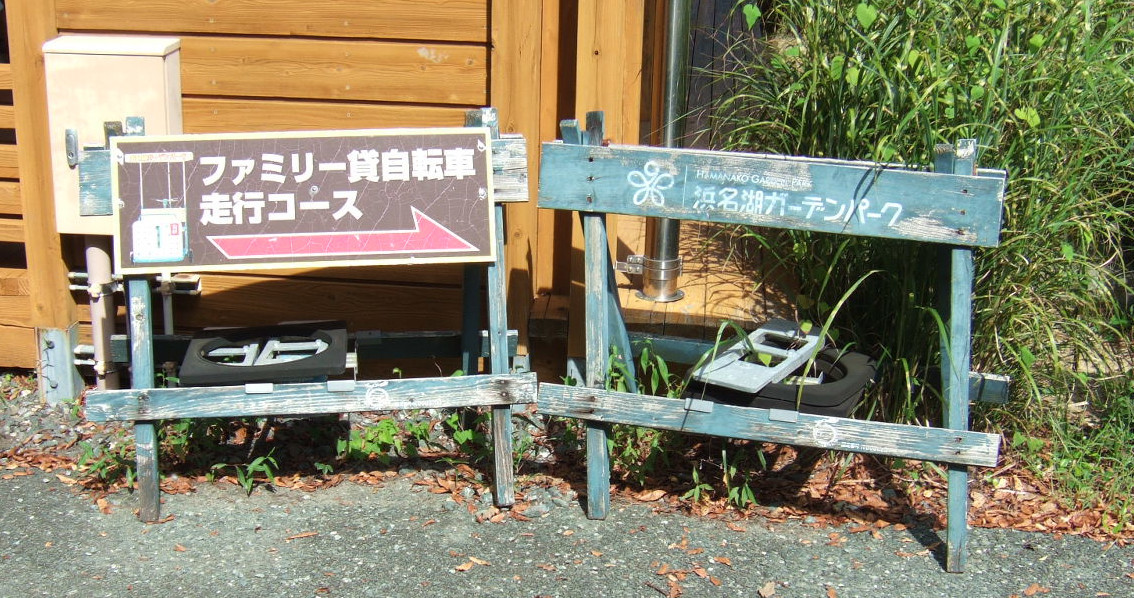 A wooden sign reading (in translation): “Family Rental Bicycle (literally ‘rider-propelled vehicle’) Path”