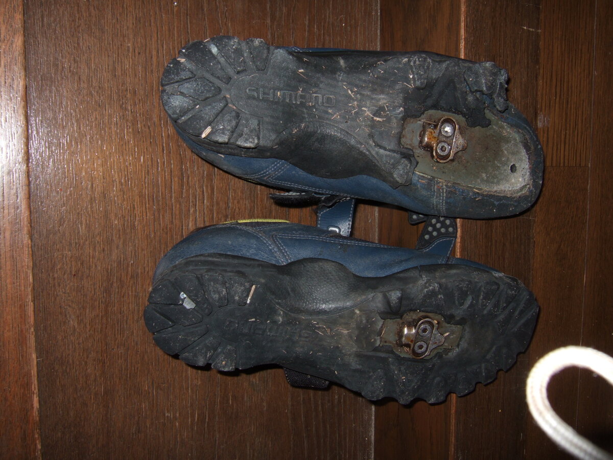 Biking shoe bottoms with chunks of their soles missing.