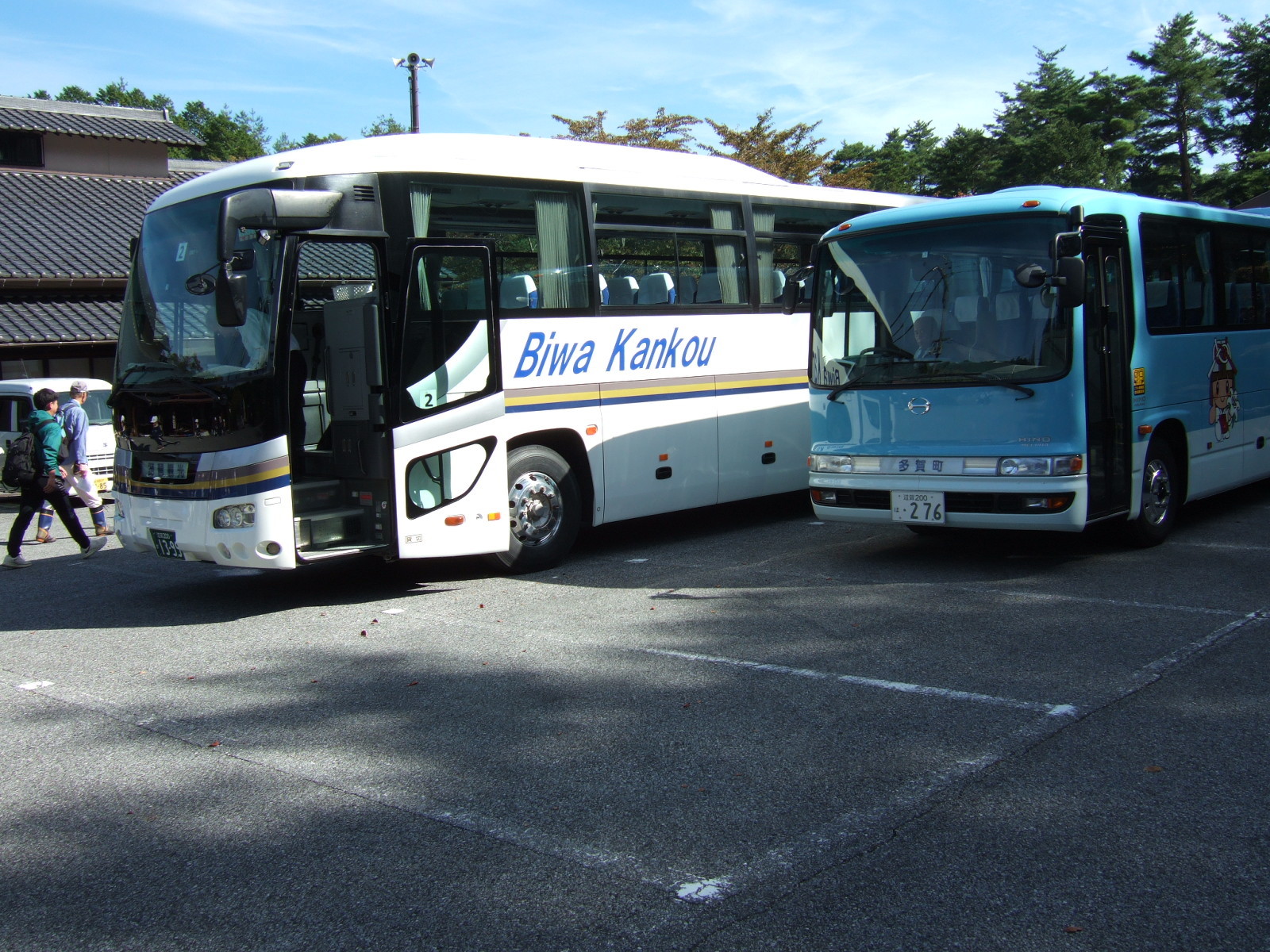 Two buses stand in a parking lot. On the side of one, the operator’s name Biwa Kankou (Biwa Tourism) is written (for Lake Biwa, lying to the north and east of Kyoto).