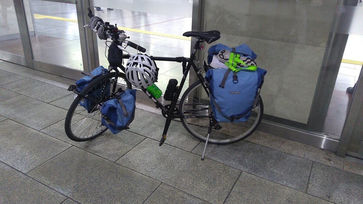 A touring bicycle with four panniers, standing outside the Nagoya shinkansen station.