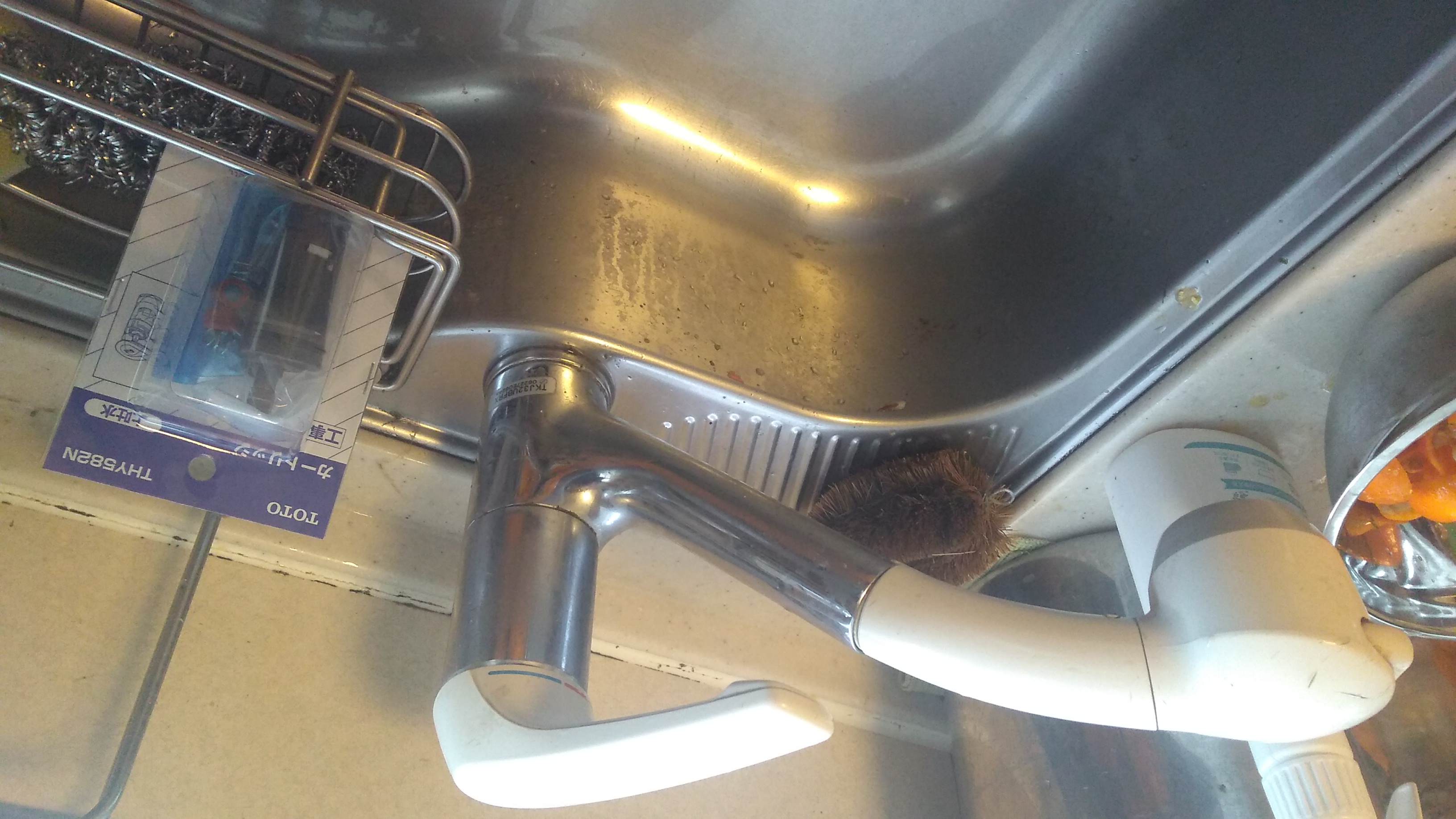 A kitchen faucet, with a replacement cartridge, still in its wrapping, standing next to it in the basin’s soap tray.